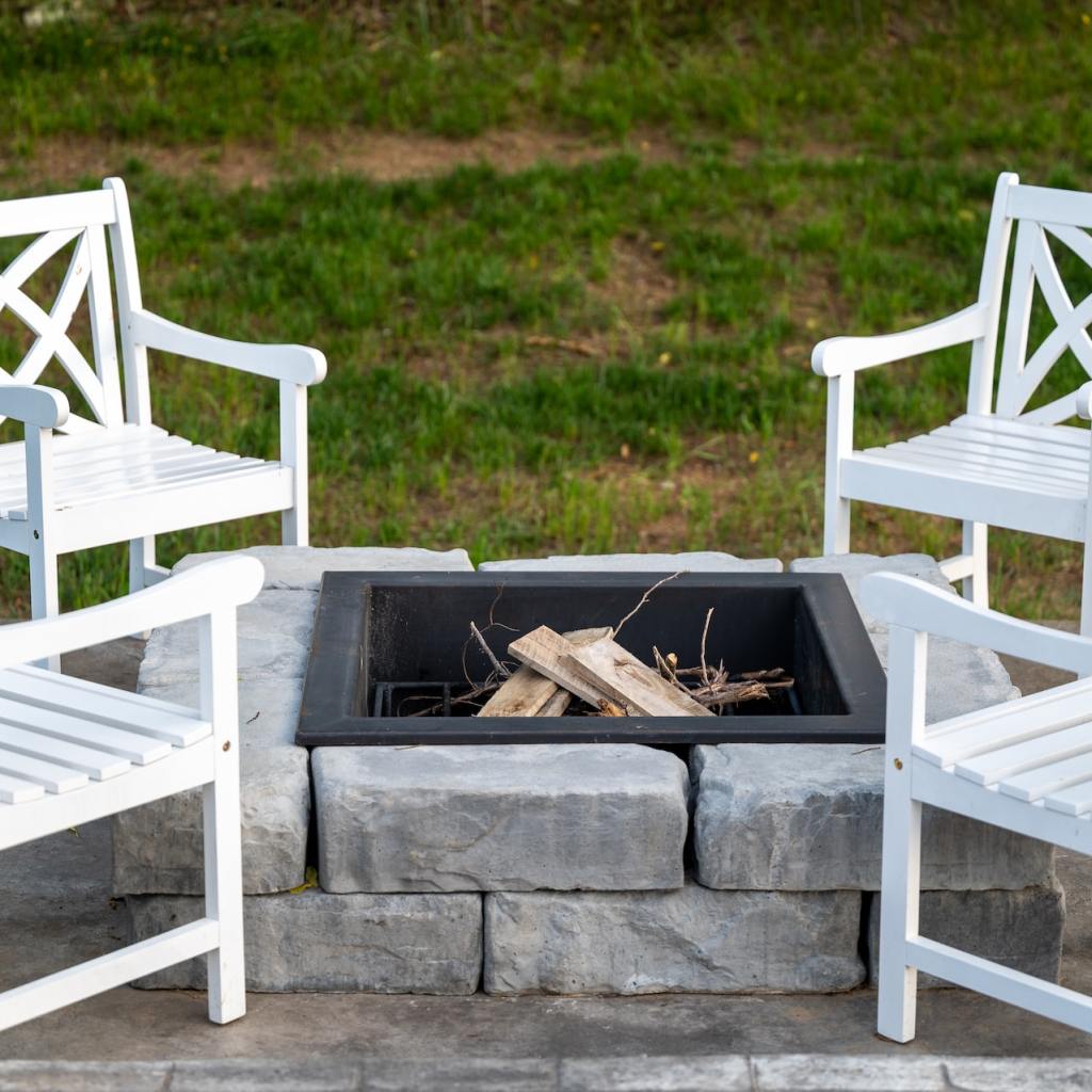Square fire pit with white chairs around it