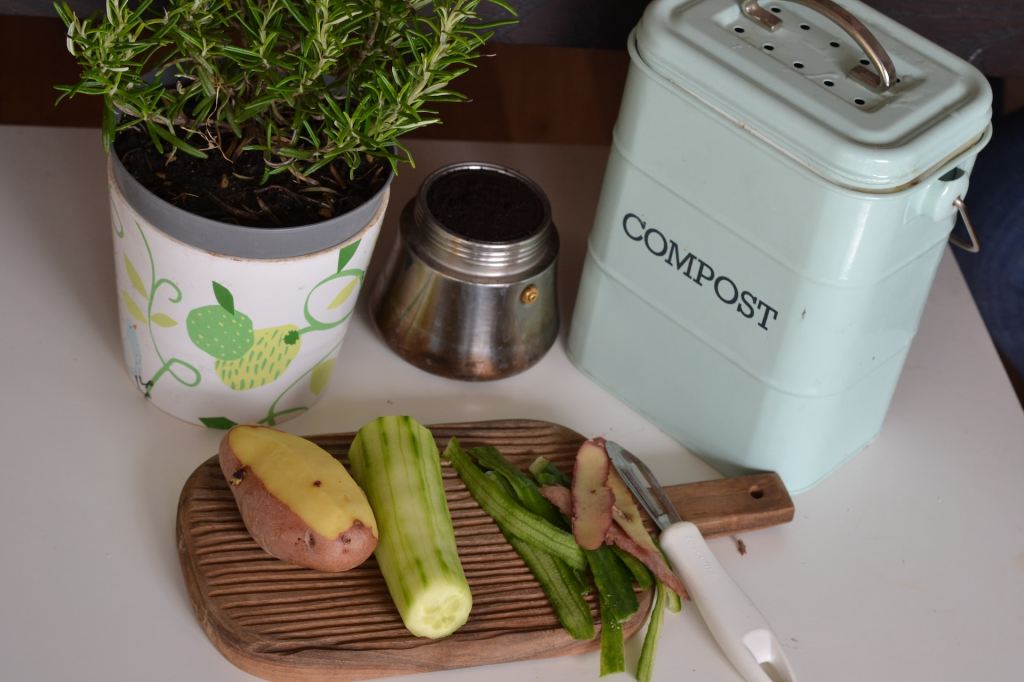 A small compost bin with food scraps next to it