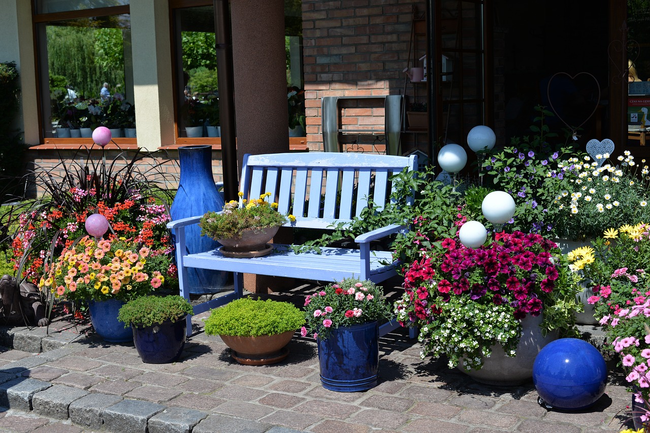 A patio with colorful potted plants surrounding a bench.