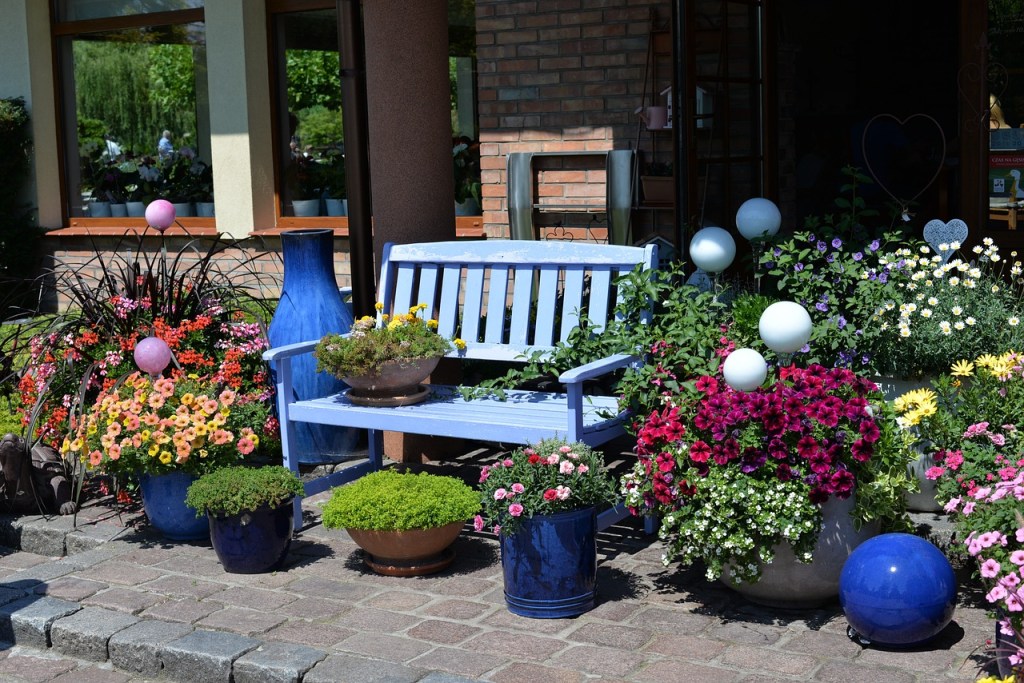 A patio with colorful potted plants surrounding a bench.