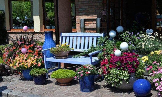 A patio with colorful potted plants surrounding a bench.