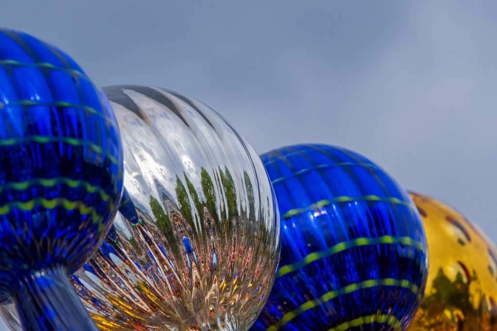 A row of blue, silver, and yellow water globes.