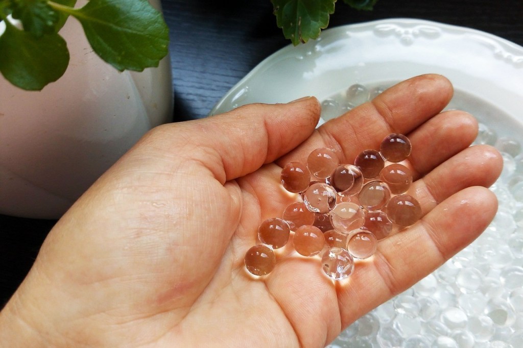 A person scooping clear water beads out of a bowl